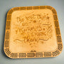 Wooden cribbage board with engraved text on a gray background