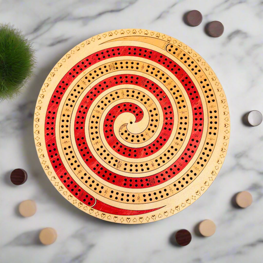 Round wooden cribbage board with red and beige spiral design on a gray background