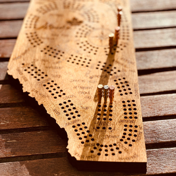 Wooden cribbage board with pegs on a wooden surface