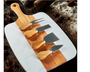 Marble cutting board with wooden handles and four cheese tools on a rustic background
