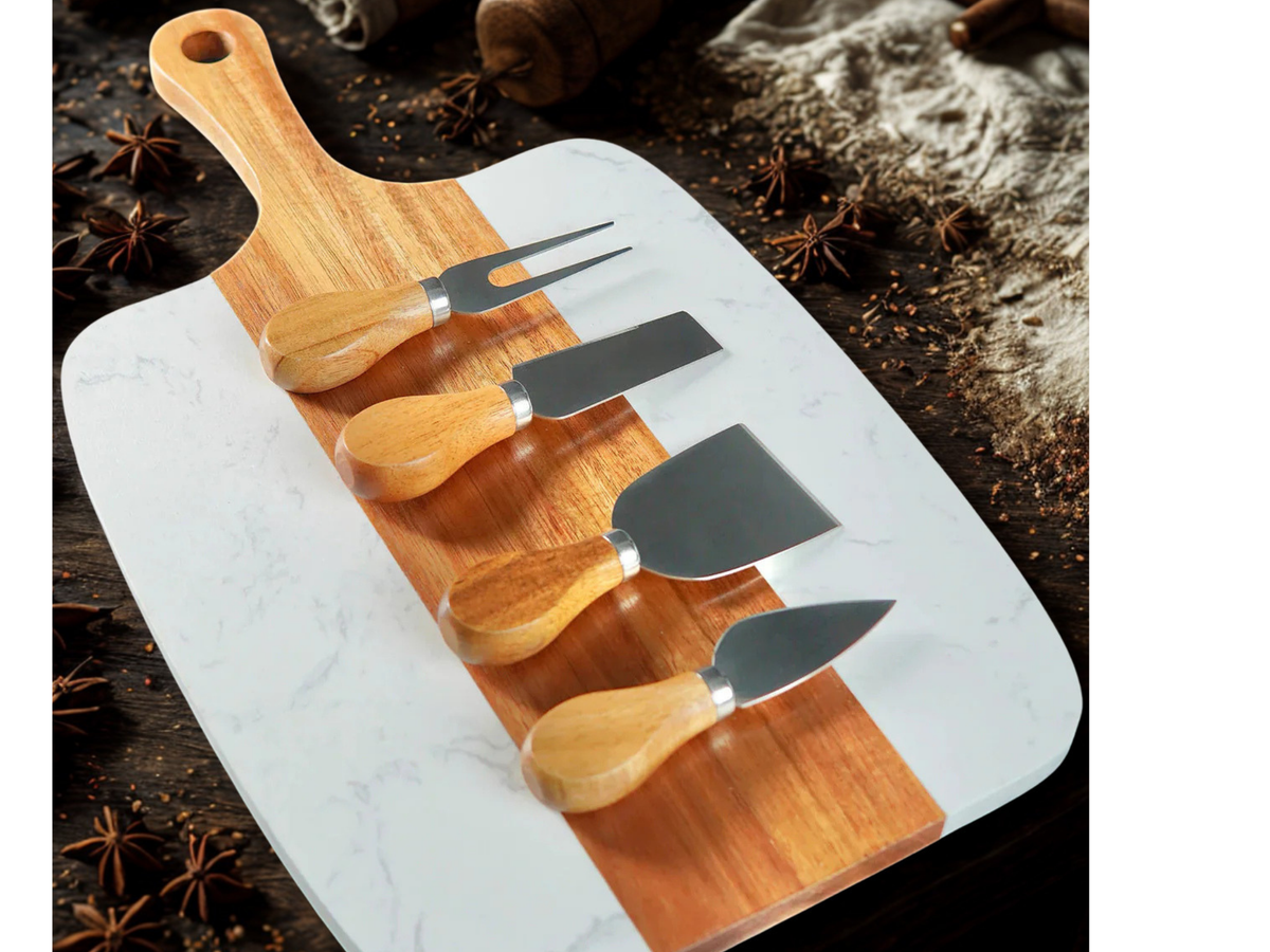 Marble cutting board with wooden handles and four cheese tools on a rustic background