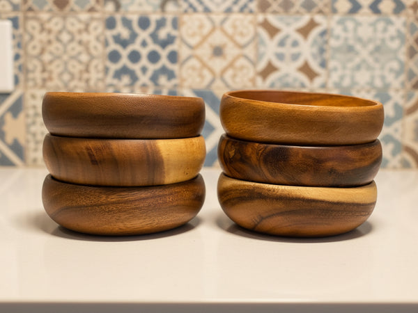 Stacks of wooden bowls on a surface with a patterned wall in the background