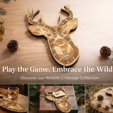 Wooden deer-shaped cribbage board on a wooden surface with glasses and cards, surrounded by pine cones and branches.