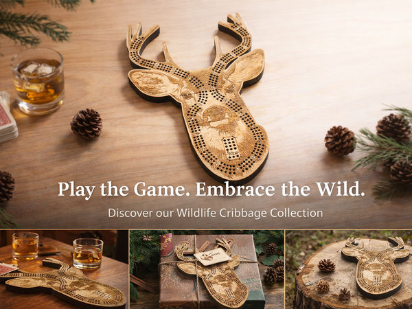 Wooden deer-shaped cribbage board on a wooden surface with glasses and cards, surrounded by pine cones and branches.