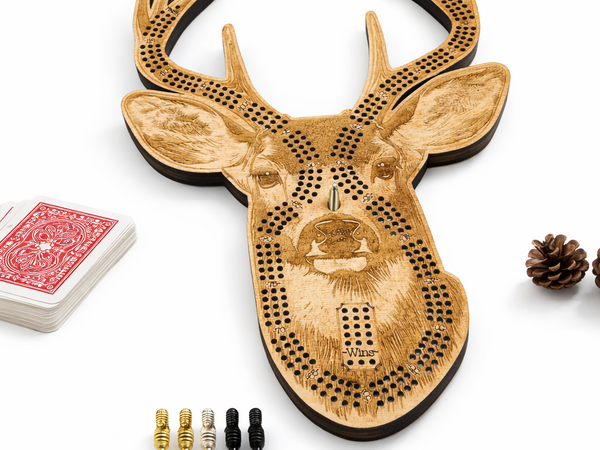 Wooden deer head cribbage board with playing cards and pegs on a white background