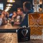 Bottle of amber liquid with 'TOEWS' branding and a black flask on a textured surface.