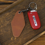 Red keychain with SRT logo on a brown leather tag, placed on a wooden surface.