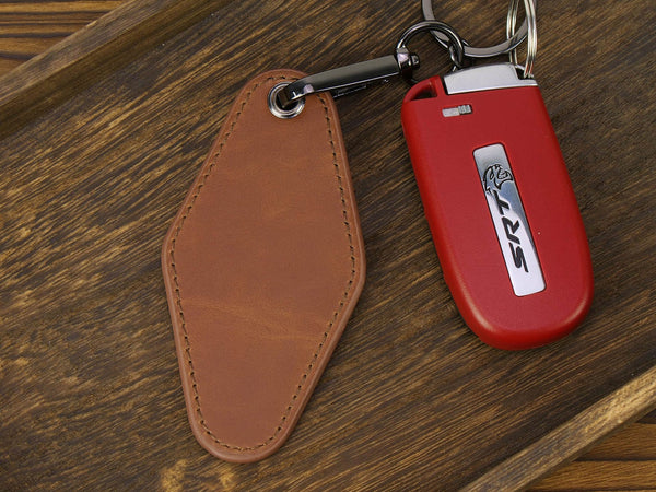 Red keychain with SRT logo on a brown leather tag, placed on a wooden surface.