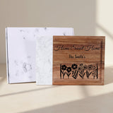 Wooden cutting board with engraved 'Home Sweet Home The Smiths' text and floral design on a white marble surface.