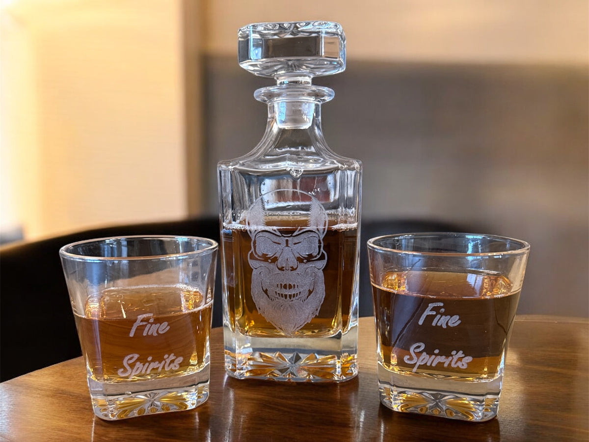 Whiskey decanter and two glasses with 'Fine Spirits' text on a wooden surface.