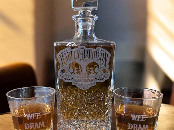 Harley Davidson whiskey bottle with two glasses on a wooden surface