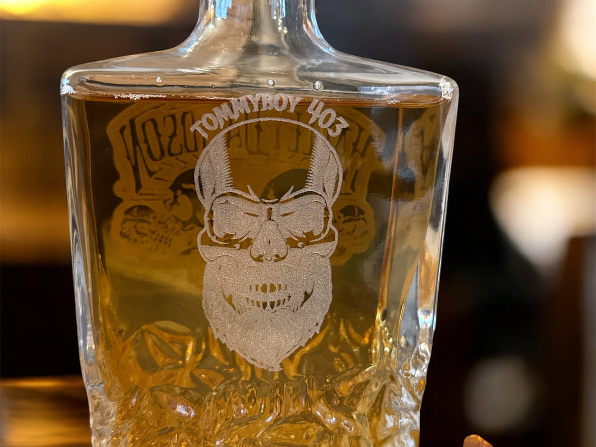 Glass bottle with engraved design and text on a blurred background