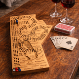 Wooden cribbage board with playing cards and wine glasses on a wooden table.