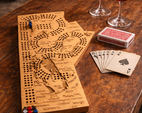 Wooden cribbage board with playing cards and wine glasses on a wooden table.