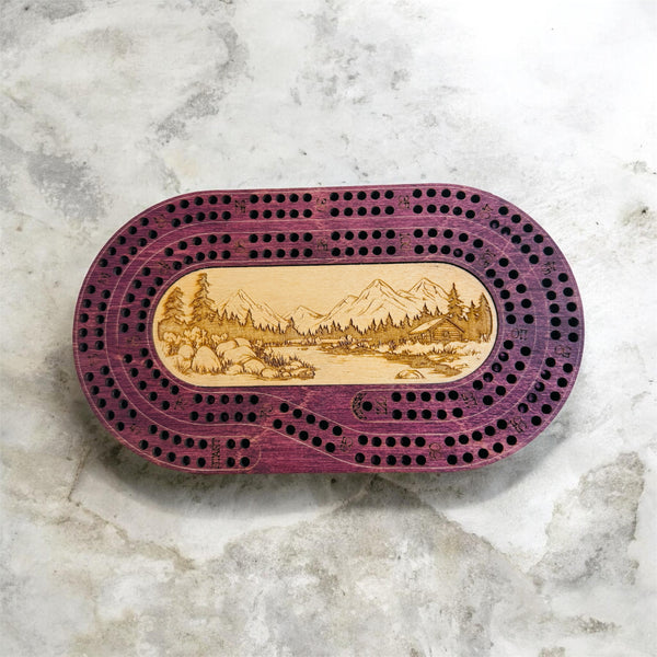 Wooden cribbage board with mountain design on a marble surface