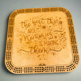 Wooden cribbage board with engraved text on a gray background