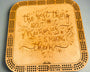 Wooden cribbage board with engraved text on a gray background