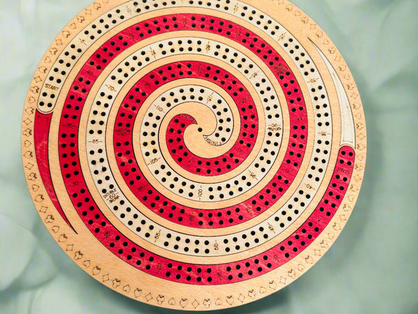 Circular wooden cribbage board with spiral design on a gray background