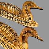 Two wooden duck-shaped cribbage boards on a wooden surface.
