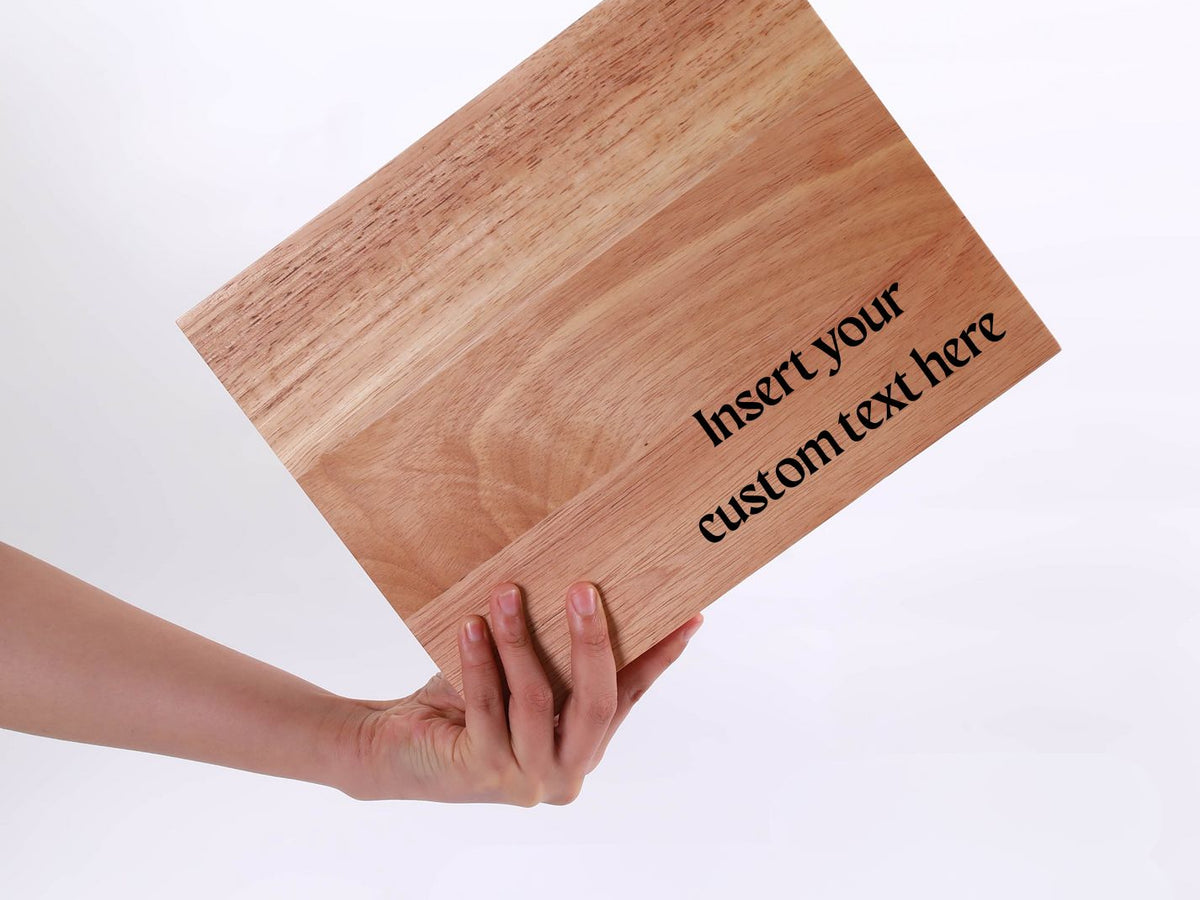 Wooden cutting board with 'Insert your custom text here' text, held by a hand on a white background