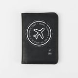 Black passport holder with airplane design and text on a white background