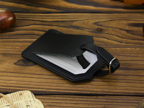Black leather luggage tag on a wooden surface with a newspaper underneath