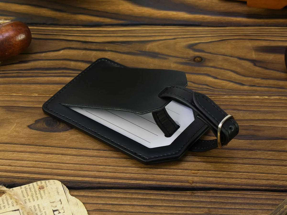 Black leather luggage tag on a wooden surface with a newspaper underneath