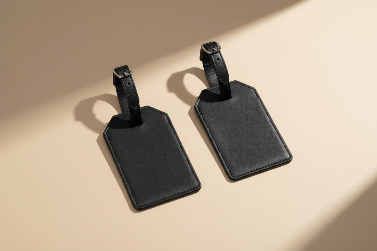 Two black leather luggage tags on a white background