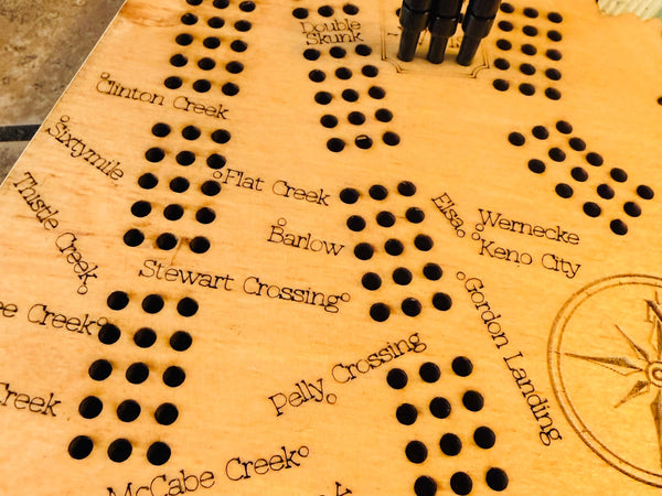 Wooden cribbage board with pegs on a checkered tablecloth