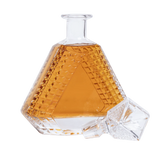Hexagonal glass decanter with amber liquid on a white background