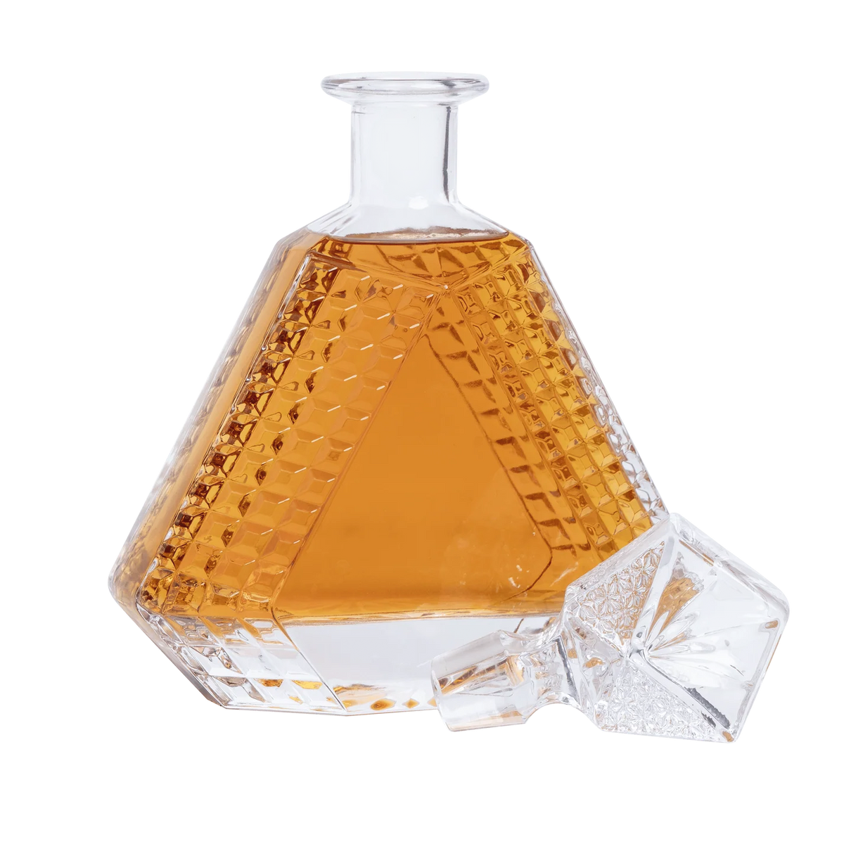 Hexagonal glass decanter with amber liquid on a white background