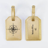 Two gold luggage tags with compass design and text on a white background