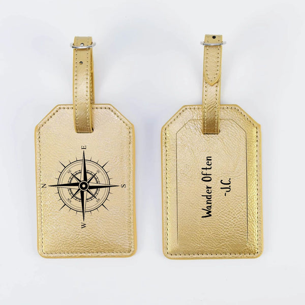 Two gold luggage tags with compass design and text on a white background