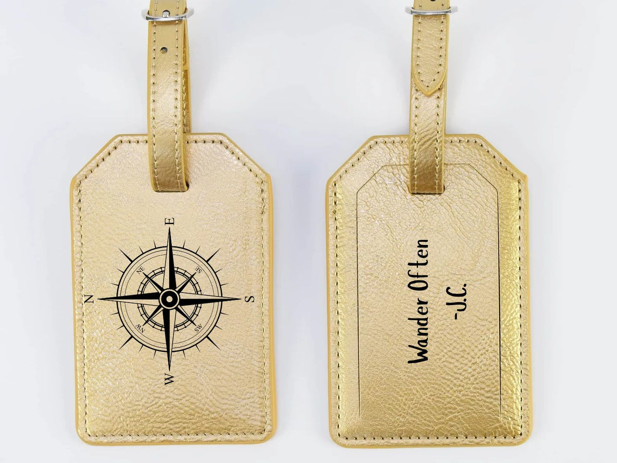 Two gold luggage tags with compass design and text on a white background