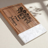 Wooden cutting board with floral design and text on a white background