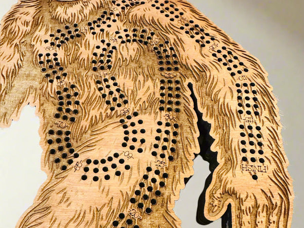 Wooden Bigfoot cribbage board with cut-out design on a light background