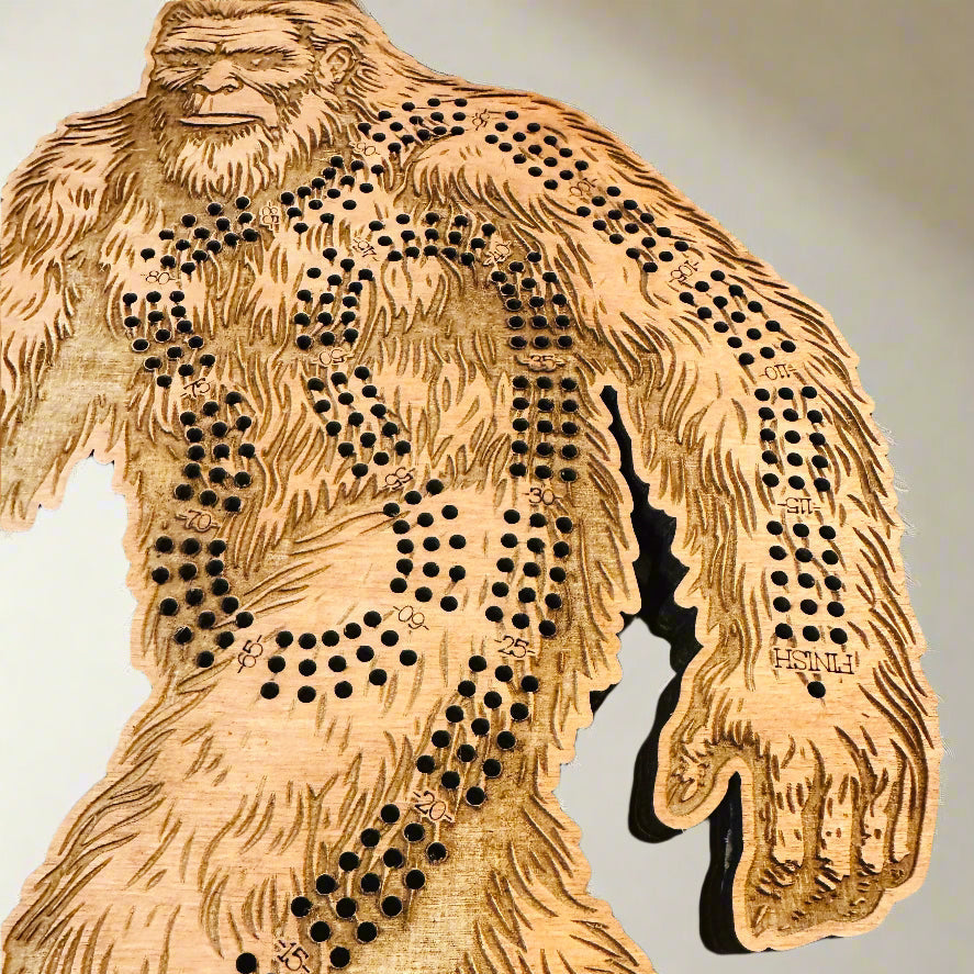 Wooden Bigfoot cribbage board with cut-out design on a light background