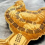 Wooden game board shaped like a rooster on a gray surface
