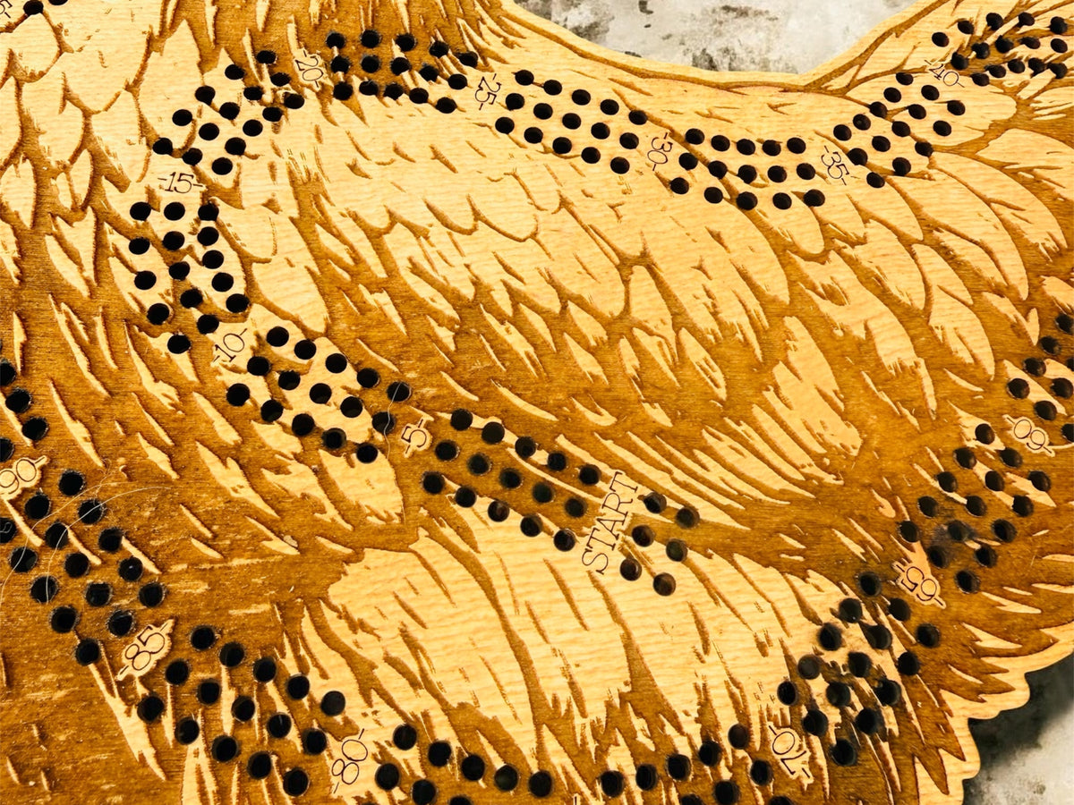 Close-up of a wooden cribbage board with pegs on a stone surface