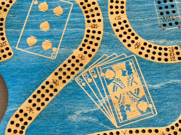 Close-up of a cribbage board with playing card symbols on a blue background