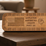 Wooden cribbage board with engraved American flag, text, and eagle design on a plain background.