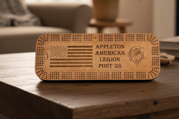 Wooden cribbage board with engraved American flag, text, and eagle design on a plain background.