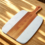 Marble-patterned cutting board with wooden handle on a wooden surface