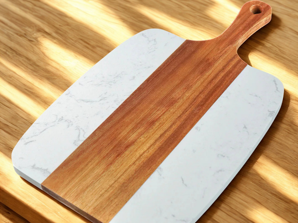 Marble-patterned cutting board with wooden handle on a wooden surface