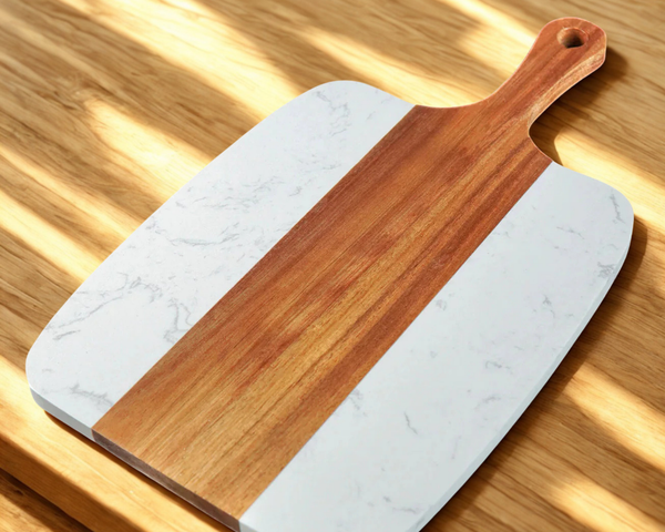 Marble-patterned cutting board with wooden handle on a wooden surface