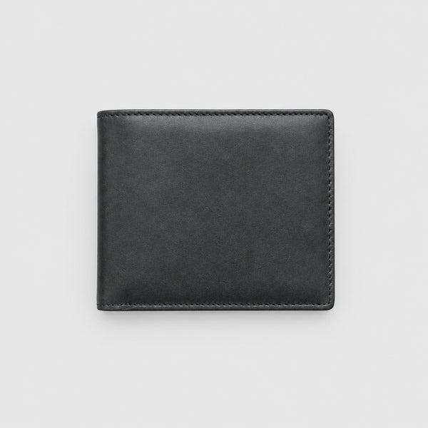 Black leather wallet on a wooden surface with American flag, rope, and spurs.