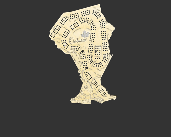 A novelty Ontario-shaped cribbage board made from a cut-out sheet of cream-colored paper, featuring printed map details, a small maple leaf, and the word 'Ontario' in script, set against a dark background.