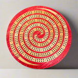 Round wooden cribbage board with red and beige spiral design on a gray background