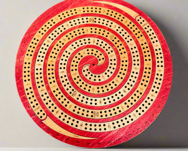 Round wooden cribbage board with red and beige spiral design on a gray background