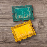 Two decorative travel size  cribbage boards cards size with engraved designs on a wooden surface